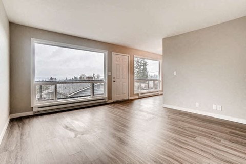 an empty living room with a large window and wooden floors